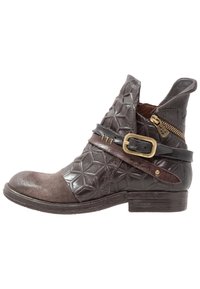 Bruine leren enkellaars met een gestructureerd patroon op het oppervlak, een suède neuskap, een zijrits en een bruine leren riem met een messing gesp.