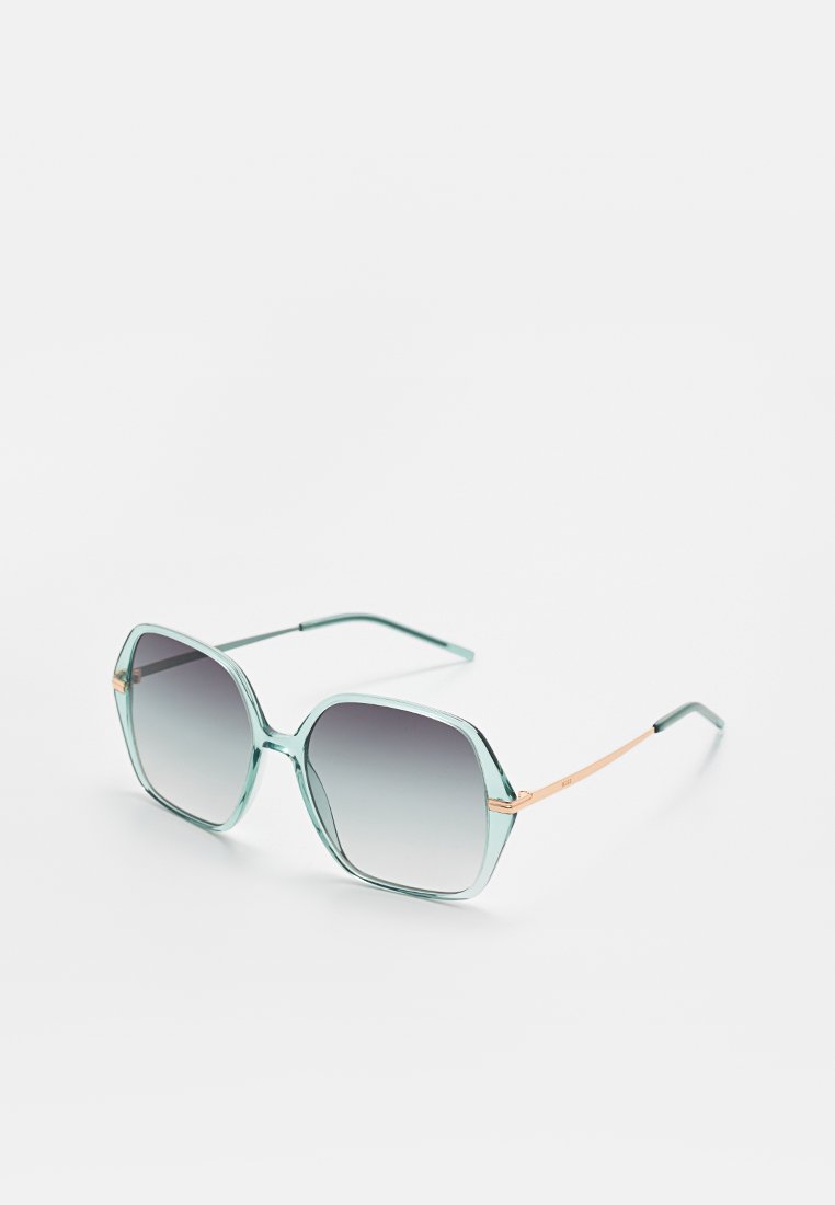 A pair of hexagonal sunglasses with transparent teal frames, gradient gray lenses, and thin rose-gold accents on the temples.