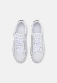 Sneakers in pelle bianca con punte arrotondate, allacciatura frontale e accenti laterali sottili. Branding visibile sulla linguetta e sulla soletta interna.
