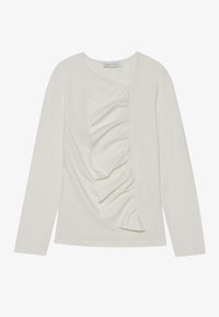 Long-sleeve, cream-colored top made of soft fabric with a diagonal ruffle detail on the front and a rounded neckline.