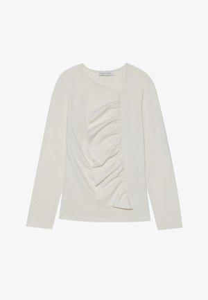 Long-sleeve, cream-colored top made of soft fabric with a diagonal ruffle detail on the front and a rounded neckline.