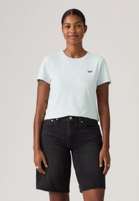 Ανοιχτό μπλε βαμβακερό T-shirt με κοντά μανίκια και στρογγυλή λαιμόκοψη, με μικρό κόκκινο λογότυπο Levi's. Συνδυάζεται με μαύρα τζιν σορτς.