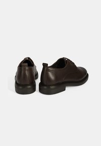 Bruine leren schoenen met een textuur, ronde neus en stevige rubberen zolen. Voorzien van veters en een lage hak.