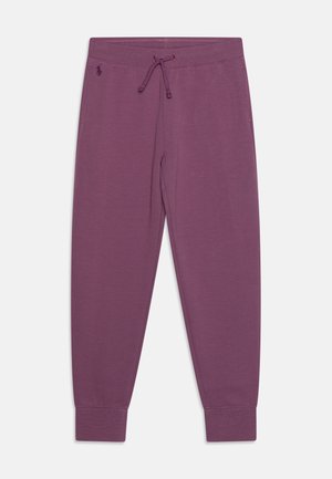 Lila zulaufende Jogginghose mit Kordelzug am Bund, gerippten Bündchen und kleinem gesticktem Logo an der linken Hüfte.