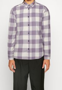 Lila-weiße karierte Langarmbluse mit Kragen, Knopfleiste und schwarzen Knöpfen. Der Stoff hat eine weiche Textur und einen lässigen Schnitt.