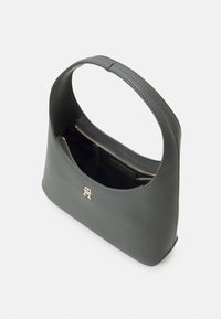 Sac à main en cuir gris avec une bandoulière large, une fermeture éclair dorée et un petit logo doré sur le devant, montré partiellement ouvert sur fond blanc.
