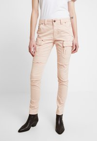 Světlé růžové cargo kalhoty se slim fit, nabízející několik kapes, zapínání na knoflík a hladkou texturu látky. Ozdobeny zlatými detaily.