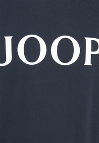 Camiseta azul marino de algodón suave, con un gran texto blanco "JOOP" en la parte frontal en una fuente audaz y limpia.