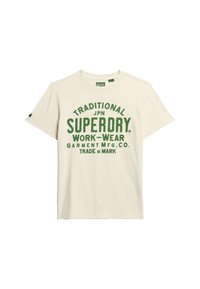 Camiseta de algodón color crema de manga corta con texto verde en negrita: "TRADITIONAL JPN SUPERDRY WORK-WEAR GARMENT MFG. CO. TRADE MARK."
