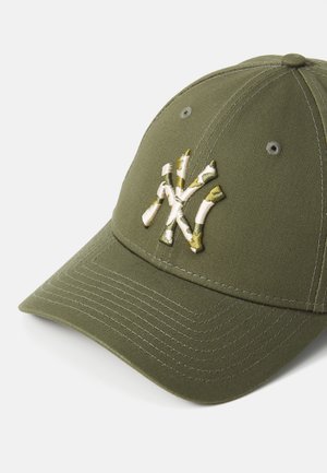 Green cotton baseball cap featuring a structured design, tonal stitched accents, and an embroidered logo on the front in camouflage colors.