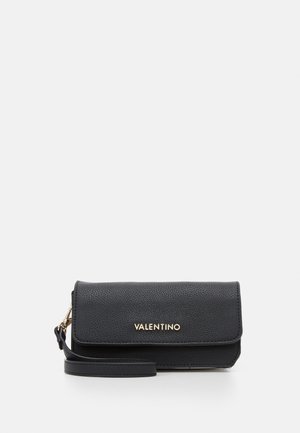 Sac à main en cuir noir avec une finition texturée, rabat repliable, logo doré et bandoulière détachable. Forme rectangulaire compacte.