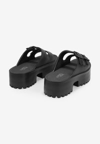 Sandali platform neri realizzati in materiale liscio, con punte scoperte e fasce larghe con fibbia laterale. Suola spessa e testurizzata per una buona aderenza.
