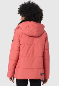 Coral puffer jacket with a hood, featuring quilted stitching and a faux fur trim. Includes branded tag on the left sleeve.