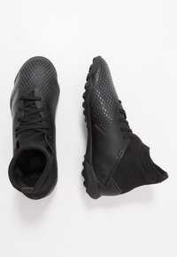 Mustat urheilukengät, joissa on teksturoitu päällinen, sukka-tyylinen kaulus ja kumipohja, jossa on hyvin näkyvät kuvioinnit. Narut ovat läsnä.