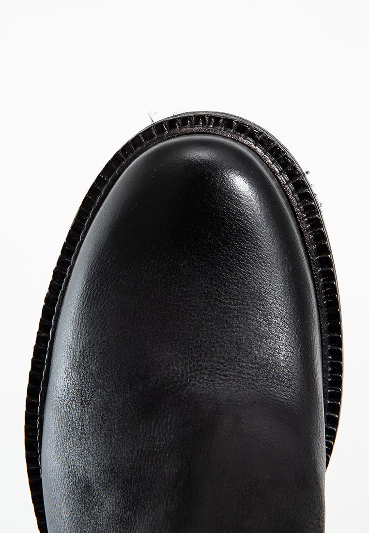 Bottine en cuir noir avec un bout arrondi, finition texturée et couture contrastante le long du bord de la semelle. Design épuré.