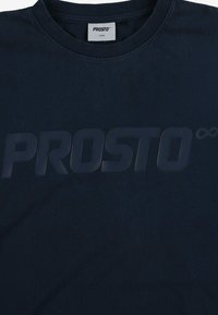 Granatowa bawełniana koszulka z dużym, wystającym logo "PROSTO" na środku. Żebrowany okrągły dekolt i miękka, gładka faktura.