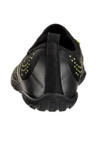 Chaussure de sport noire avec un tissu texturé et des accents lisses et brillants. Détails en vert fluo sur les côtés et la languette. Semelle en caoutchouc pour une meilleure adhérence.