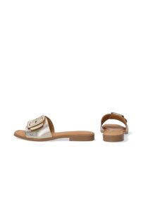 Metalliske guld slide-sandaler med en struktureret rem med en stor spænde, sat på en lys brun flad sål. Enkel åbent bag-design.