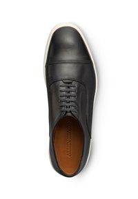 Scarpa in pelle nera con punta rotonda, suola bianca, sei fori per i lacci e cuciture tonali discrete lungo la parte superiore. La fodera interna è color nocciola.