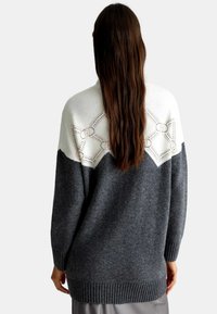 Maglione lavorato a maglia grigio con una scollatura color crema che presenta un motivo geometrico. Texture morbida e orlo a coste in vita e ai polsi.