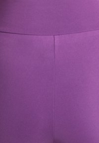 Paarse legging van een gladde, rekbare stof. Voorzien van een hoge tailleband en een middennaad, voor een aansluitende pasvorm en comfort.