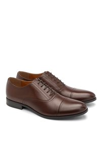 Pantofi de piele maro cu finisaj neted, vârf rotund și cinci găuri pentru șireturi. Prezintă cusături discrete și o talpă joasă din cauciuc negru.