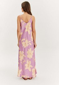Maxi šaty z světlého fialového materiálu s velkými žlutými květinovými vzory, tenkými ramínky a designem ve tvaru V na zádech. Hladká textura, splývavý silueta.
