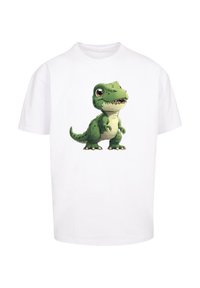 White cotton t-shirt featuring a cartoon green dinosaur graphic with brown accents, wide stance, large eyes, and a playful expression.