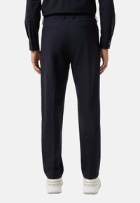 Pantalons navy à coupe décontractée, avec une taille élastique et deux poches arrière. Associés à des baskets blanches avec des accents de logo.