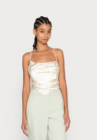 Camisola de cetim floral em verde suave e branco, com alças finas e um corte descontraído, combinada com calças ajustadas em verde claro.