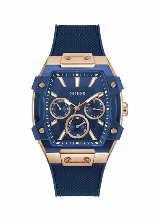 Montre analogique bleue avec des accents dorés, dotée d'un bracelet texturé, de plusieurs cadrans et d'un cadran hexagonal audacieux. Nom de la marque "Guess" affiché en évidence.