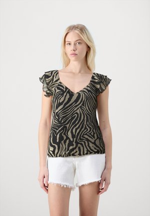 Schwarz-beige gestreiftes Zebra-Muster-Oberteil mit V-Ausschnitt und Rüschensleeves, kombiniert mit weißen, ausgefransten Shorts. Glattes Material mit leichter Textur.