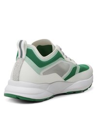 Baskets de sport blanches et vertes avec panneaux en mesh, semelle épaisse amortie, lacets à l'avant et languette au talon, vues de l'arrière.