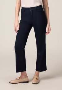 Pantaloni in denim blu navy scuro con vestibilità a gamba dritta, caratterizzati da piccoli dettagli metallici e una chiusura classica con bottone.