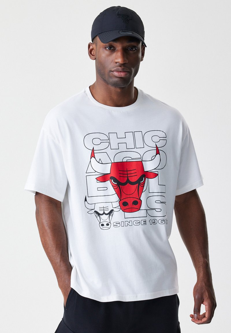Bijela pamučna majica koja prikazuje veliki crveni i crni grafički prikaz bika s natpisom "CHICAGO BULLS OD 1966." u debelom fontu. Kratki rukavi.