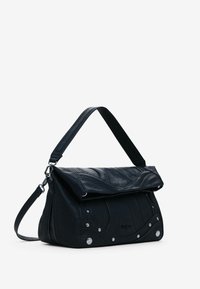 Schwarze Lederhandtasche mit umklappbarem Deckel, geschwungenen Nähten, Reißverschluss und silberfarbenen Hardware-Akzenten. Inklusive abnehmbarem Schulterriemen.