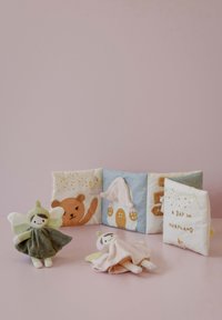 Soft toys and fabric books in pastel colors. Features include a green fairy, a bear, and whimsical illustrations on textured pages.
