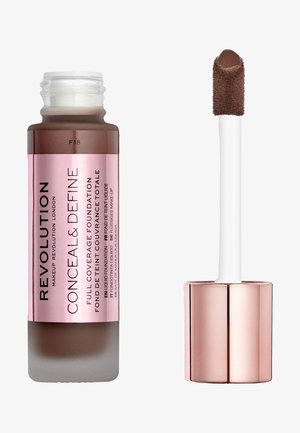 Fondotinta liquido marrone in un flacone trasparente con etichetta rosa. Presenta un applicatore bianco con punta morbida e testurizzata.