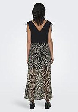 Robes : haut noir sans manches avec dos en V, longue jupe fluide arborant un motif zébré tourbillonnant beige et noir, associée à des chaussures noires.