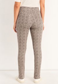 Leggings avec un motif texturé gris, présentant une taille haute et une coupe ajustée. Tissu doux et détails de couture minimaux.