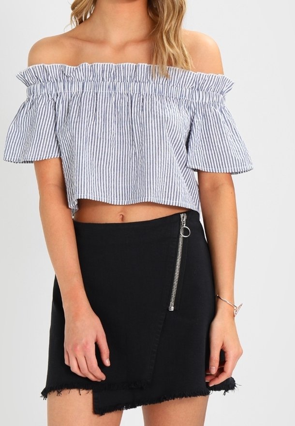 Modrý a bílý pruhovaný crop top s odhalenými rameny a volánkovým výstřihem, spárovaný s černou denimovou sukní s bočním zipem a roztrhaným lemem.