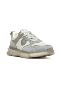 Zapatilla deportiva gris que combina materiales de malla y gamuza. Suela redondeada con acentos transparentes y un logo en el lateral.