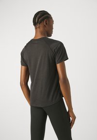 T-shirt de sport noir à manches courtes, texture en maille et ourlet arrondi. Doté de manches raglan pour une meilleure mobilité.