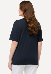 Camiseta de manga corta en azul marino con un corte relajado, tejido suave y un diseño liso. La parte posterior tiene un escote redondeado y un dobladillo recto.