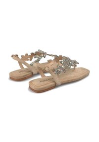 Sandali beige con suola piatta, caratterizzati da un design floreale decorativo con strass sui cinturini. Realizzati in materiale scamosciato.