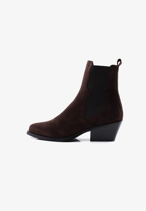 Hnědé semišové kotníkové boty s černými elastickými bočními panely, nízkým zvednutým podpatkem a poutkem na bílém pozadí.