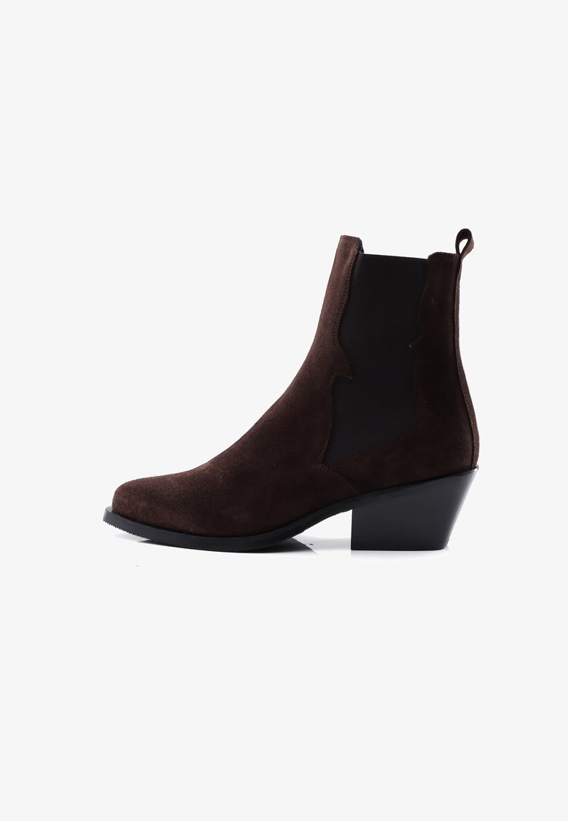 Bota de tobillo de ante marrón con paneles laterales elásticos negros, tacón bajo de bloque y lengüeta, sobre fondo blanco.