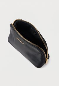 Crna kožna torbica s zlatnim patentnim zatvaračem i metalnim detaljima. Ima glatku teksturu i utisnuti logotip na vanjskoj strani. Prikazan je otvoreni pogled na unutrašnjost.