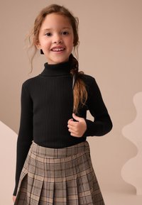 Sort ribstrikket rullekravetrøje kombineret med et ternet plisseret nederdel i neutrale toner. Outfitet har tekstureret stof og et generelt tætsiddende design.