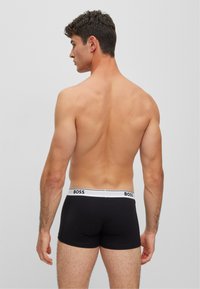 Boxer-briefs noirs avec une ceinture blanche portant le logo "BOSS". Tissu lisse à coupe ajustée, design minimaliste et sans motifs supplémentaires.